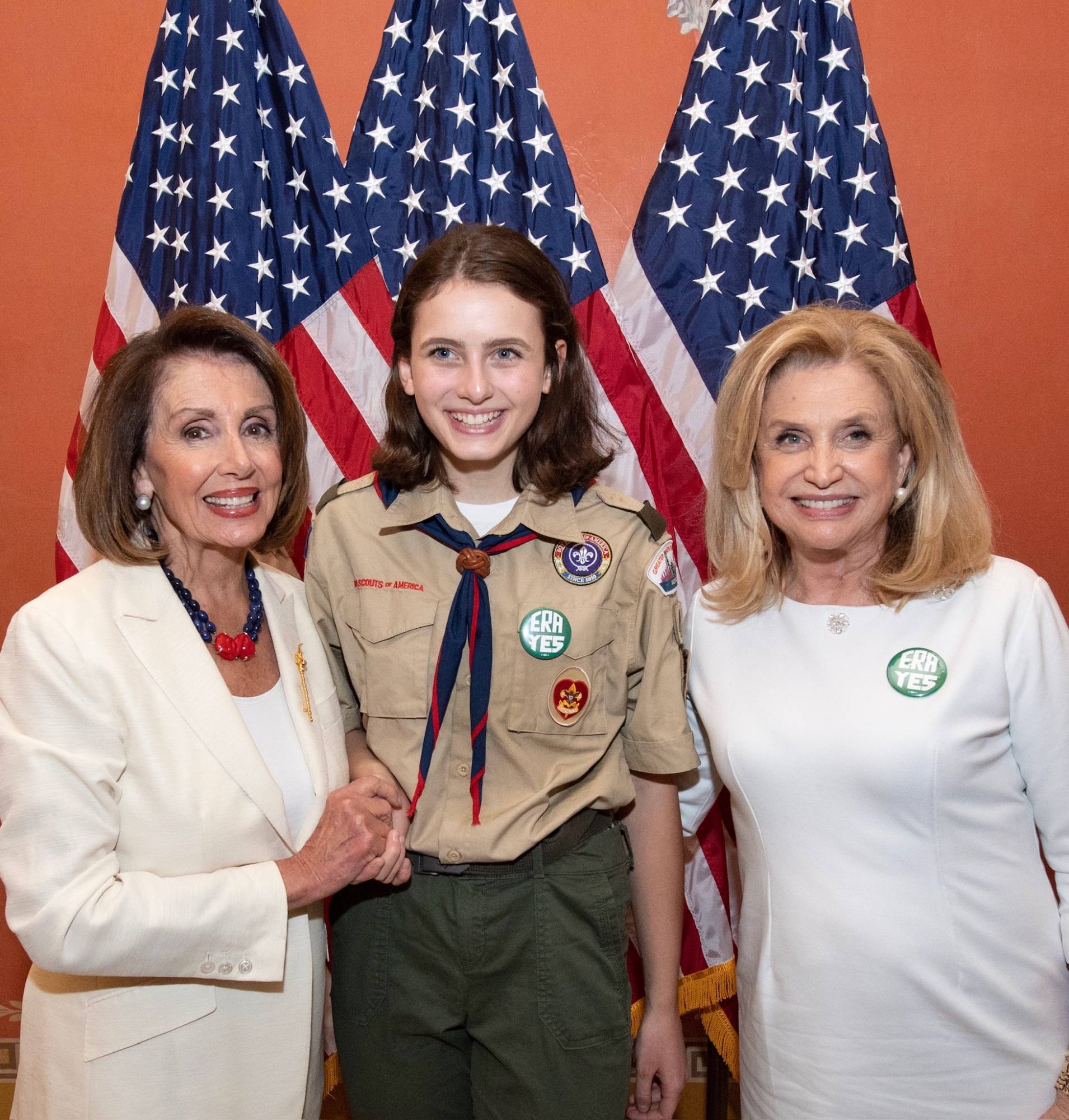 Sydney in scout uniform standing with two guests in front of American flags